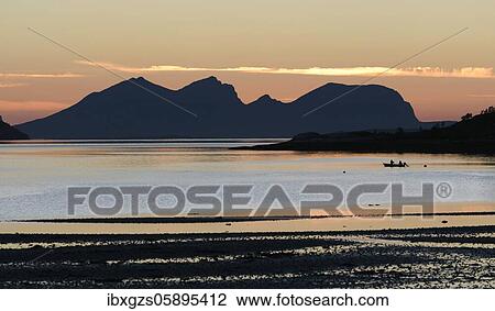 Silhouette of a mountain peak in the twilight at a fjord, in front small fishing boat, Engavågen, Nordland, Norway, Europe View Large Photo Image Stock Image - Silhouette of a mountain peak in the twilight at a fjord, in front small fishing boat, Engavågen, Nordland, Norway, Europe. Fotosearch