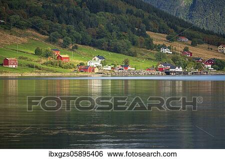 Stock Photograph - Small settlement on a fjord, behind mountains with wooded slopes, Dalsgrenda, Nordland, Norway, Europe. Fotosearch