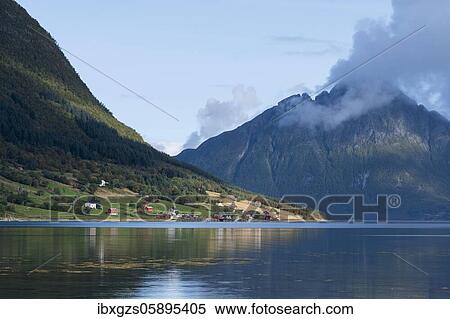 Stock Photography - Small settlement on a fjord, behind mountains with wooded slopes, Dalsgrenda, Nordland, Norway, Europe. Fotosearch