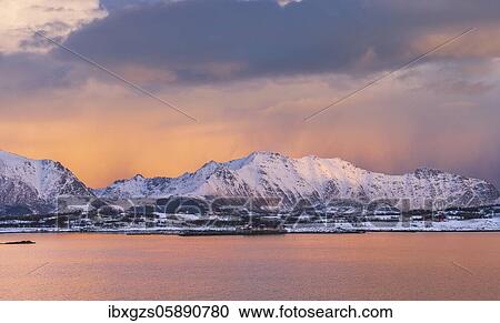 Stock Image - Snowy landscape at sea and fjord, cloud atmosphere, warm evening light, Nordland, Lofoten, Norway, Europe. Fotosearch