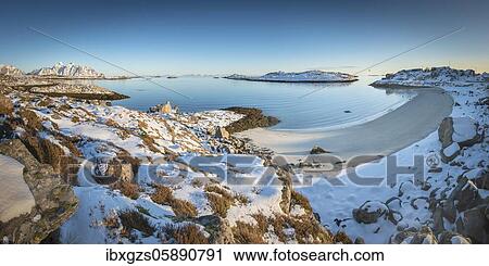 Stock Image - Snowy white sandy beach in a winterly bay, blue sea, behind Lofoten peaks, Nordland, Lofoten, Norway, Europe. Fotosearch