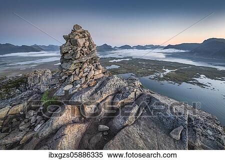Stone pyramid at the top of Hoven at dusk, mountains on the horizon and fjords with clouds, Gimsøy, Lofoten, Nordland, Norway, Europe View Large Photo Image Stock Photography - Stone pyramid at the top of Hoven at dusk, mountains on the horizon and fjords with clouds, Gimsøy, Lofoten, Nordland, Norway, Europe. Fotosearch