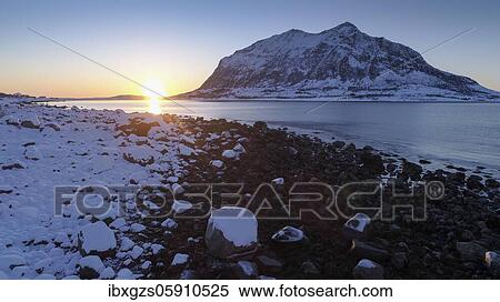 Stock Photography - Sunrise on a rocky beach in winter, mountain in the sea behind, Meløy, Nordland, Norway, Europe. Fotosearch