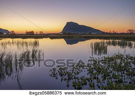 Stock Photography - Swampland, dusk reflected in water surface, behind mountain silhouette on the horizon, Gimsøy, Lofoten, Nordland, Norway, Europe. Fotosearch
