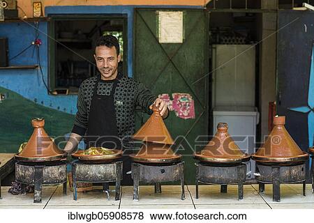 Stock Photo - Tajine, a man offers traditional Moroccan food prepared on charcoal fire in typical Tajine pots at a stand. Fotosearch