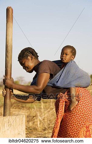 Tonga woman with child on her back pounding grain, Lake Kariba, Zambia, Africa View Large Photo Image Stock Photography - Tonga woman with child on her back pounding grain, Lake Kariba, Zambia, Africa. Fotosearch