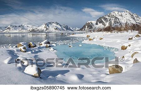 Stock Photography - Turquoise lagoon with snow surface and ice floes, behind it snow covered mountains, Kleppstad, Nordland, Lofoten, Norway, Europe. Fotosearch