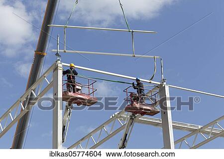 Picture - Two construction workers on working platforms, assembling the roof structure of a logistics hall, Duisburg, North Rhine-Westphalia, Germany, Europe. Fotosearch