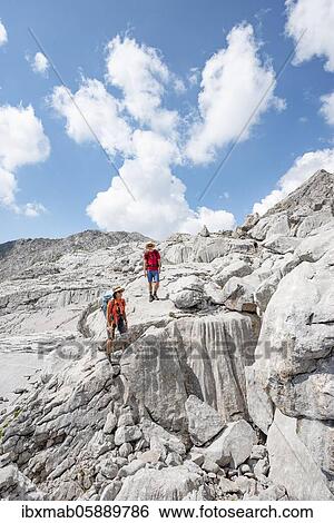 Stock Photograph - Two hikers in a landscape of washed out karst rocks, Funtenseetauern, Steinernes Meer, Berchtesgaden National Park, Berchtesgadener Land, Upper Bavaria, Bavaria, Germany, Europe. Fotosearch