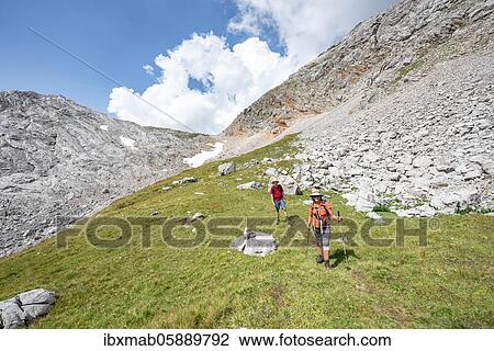 Stock Image - Two hikers on a hiking trail around the Funtenseetauern, landscape of washed out karst rocks, Steinernes Meer, Berchtesgaden National Park, Berchtesgadener Land, Upper Bavaria, Bavaria, Germany, Europe. Fotosearch