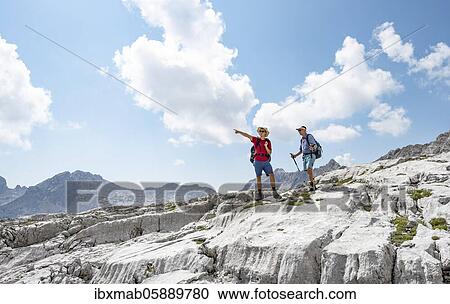 Stock Image - Two hikers on a hiking trail, hiker points into the distance, landscape of washed out karst rocks, Steinernes Meer, Berchtesgaden National Park, Berchtesgadener Land, Upper Bavaria, Bavaria, Germany, Europe. Fotosearch