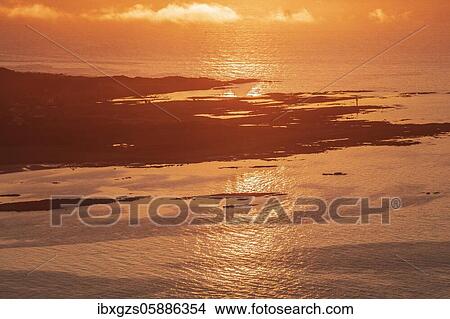 Picture - View from the top of Hoven into the sunset, in the back silhouette of the coast and sea, Vågan, Lofoten, Nordland, Norway, Europe. Fotosearch