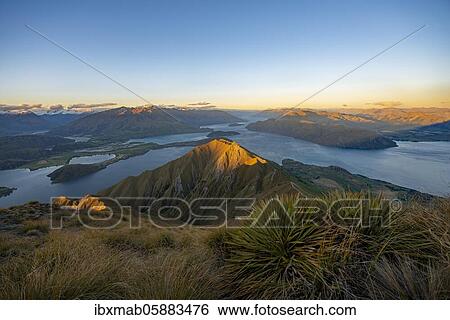 Stock Photograph - View of mountains and lake from Mount Roy, Roys Peak at sunset, Lake Wanaka, Southern Alps, Otago, South Island, New Zealand, Oceania. Fotosearch