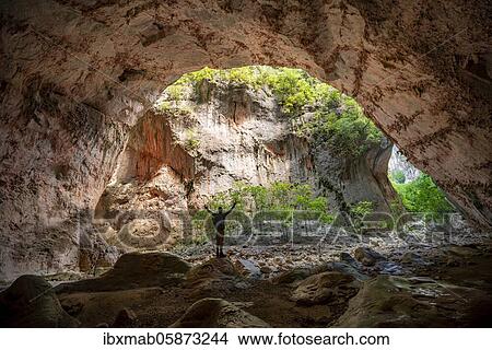 Picture - Walker stretching his arms in the air, cave Cueva de La Ermita, canyon, steep cliffs of the Garganta Verde, Sierra de Cádiz, province of Cádiz, Spain, Europe. Fotosearch