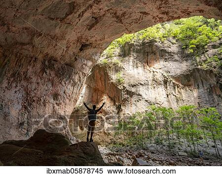 Stock Photography - Walker stretching his arms in the air, cave Cueva de La Ermita, canyon, steep cliffs of the Garganta Verde, Sierra de Cádiz, province of Cádiz, Spain, Europe. Fotosearch