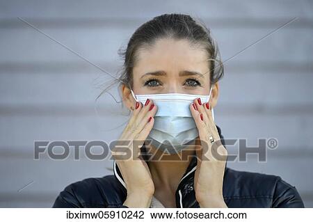 Stock Image - Woman puts on a face mask, moves her, portrait, corona crisis, Stuttgart, Baden-Württemberg, Germany, Europe. Fotosearch