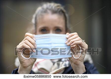 Stock Image - Woman putting on a face mask, portrait, corona crisis, Stuttgart, Baden-Württemberg, Germany, Europe. Fotosearch