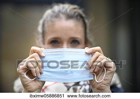 Stock Image - Woman putting on a face mask, portrait, corona crisis, Stuttgart, Baden-Württemberg, Germany, Europe. Fotosearch