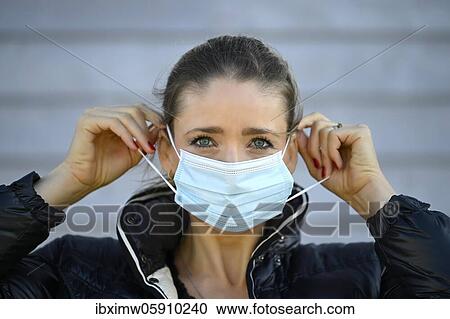 Stock Image - Woman putting on a face mask, portrait, corona crisis, Stuttgart, Baden-Württemberg, Germany, Europe. Fotosearch