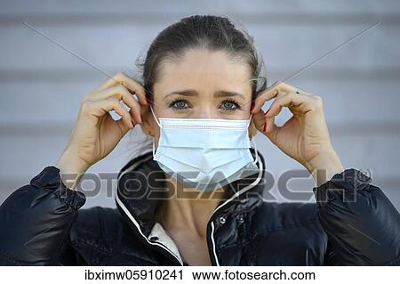 Stock Image - Woman putting on a face mask, portrait, corona crisis, Stuttgart, Baden-Württemberg, Germany, Europe. Fotosearch