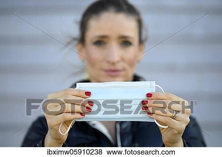 Stock Photo - Woman putting on a face mask, portrait, corona crisis, Stuttgart, Baden-Württemberg, Germany, Europe. Fotosearch