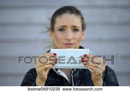 Stock Photo - Woman putting on a face mask, portrait, corona crisis, Stuttgart, Baden-Württemberg, Germany, Europe. Fotosearch