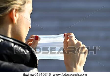 Stock Photograph - Woman putting on a face mask, portrait, corona crisis, Stuttgart, Baden-Württemberg, Germany, Europe. Fotosearch