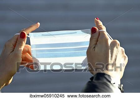 Stock Photography - Woman putting on a face mask, portrait, corona crisis, Stuttgart, Baden-Württemberg, Germany, Europe. Fotosearch