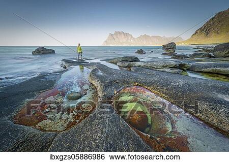 Woman standing on rocks on the beach, in front tide pool with formation Eye of Utakleiv, Vestvågøy, Nordland, Lofoten, Norway, Europe View Large Photo Image Stock Photograph - Woman standing on rocks on the beach, in front tide pool with formation Eye of Utakleiv, Vestvågøy, Nordland, Lofoten, Norway, Europe. Fotosearch