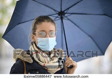 Stock Photo - Woman with face mask and umbrella, fogged glasses, portrait, corona crisis, Stuttgart, Baden-Württemberg, Germany, Europe. Fotosearch