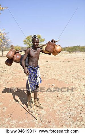 Stock Photo - Young Himba man carries food on the cattle drive, Kaokoveld, Namibia, Africa. Fotosearch
