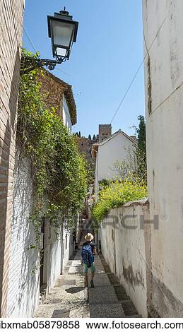 Stock Photo - Young man standing in an alley, view of the towers of the Alhambra, Albaicín district, Granada, Andalusia, Spain, Europe. Fotosearch