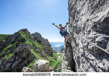 Young man stretching his arms in the air while climbing a rock face, via ferrata to the Seekarlspitze, 5-summit via ferrata, hike at the Rofan Mountains, Tyrol, Austria, Europe View Large Photo Image Stock Photograph - Young man stretching his arms in the air while climbing a rock face, via ferrata to the Seekarlspitze, 5-summit via ferrata, hike at the Rofan Mountains, Tyrol, Austria, Europe. Fotosearch