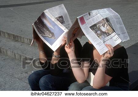 Stock Photo - Young people with newspapers above their heads, Berlin, Germany, Europe. Fotosearch