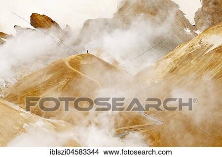 A human being in the high temperature area with steaming hot springs, rhyolite mountains and snow, Hveradalir, Kerlingarfjöll, highlands, Island View Large Photo Image Picture - A human being in the high temperature area with steaming hot springs, rhyolite mountains and snow, Hveradalir, Kerlingarfjöll, highlands, Island. Fotosearch