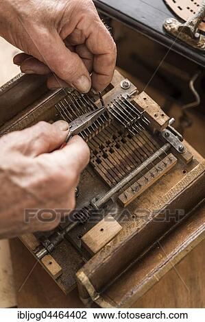 Stock Image - Barrel organ manufacture, hands with pliers connect metal reeds with wooden valves, Grassau, Upper Bavaria, Bavaria, Germany, Europe. Fotosearch