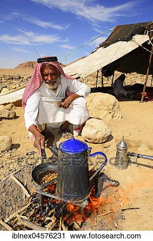 Stock Image - Bedouin preparing coffee with pan-roasted beans and kardamom, Jordan, Asia. Fotosearch