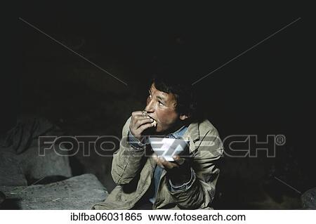 Stock Photography - Boy at meal, he dips hard flat bread in milk, Wakhi, Saradh-e-Broghil, Afghanistan, Asia. Fotosearch