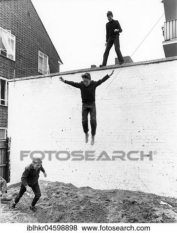 Stock Photo - Boy leaps from wall, England, Great Britain. Fotosearch