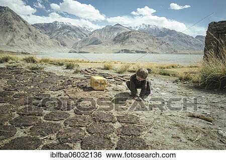 Boy plays next to cow dung flat cakes, sedentary Wakhi, behind it the mountains of the Hindu Kush, Wakhan Corridor, Saradh-e-Broghil, Afghanistan, Asia View Large Photo Image Stock Photograph - Boy plays next to cow dung flat cakes, sedentary Wakhi, behind it the mountains of the Hindu Kush, Wakhan Corridor, Saradh-e-Broghil, Afghanistan, Asia. Fotosearch
