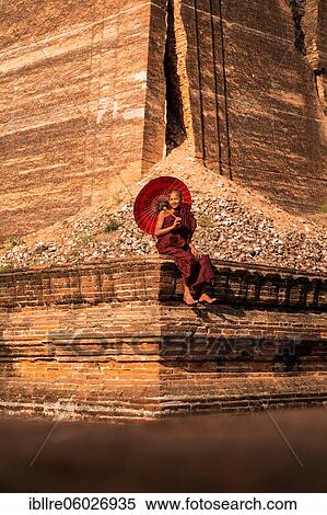 Buddhist monk sitting with red umbrella in front of Mingun Pagoda, Mingun, Myanmar, Asia View Large Photo Image Stock Photography - Buddhist monk sitting with red umbrella in front of Mingun Pagoda, Mingun, Myanmar, Asia. Fotosearch