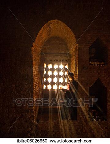 Buddhist young monk in red robe reading standing in front of rays of light in a temple, Bagan, Myanmar, Asia View Large Photo Image Stock Image - Buddhist young monk in red robe reading standing in front of rays of light in a temple, Bagan, Myanmar, Asia. Fotosearch