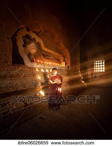 Buddhist young monk in red robe reading standing in front of rays of light in a temple, Bagan, Myanmar, Asia View Large Photo Image Stock Photo - Buddhist young monk in red robe reading standing in front of rays of light in a temple, Bagan, Myanmar, Asia. Fotosearch