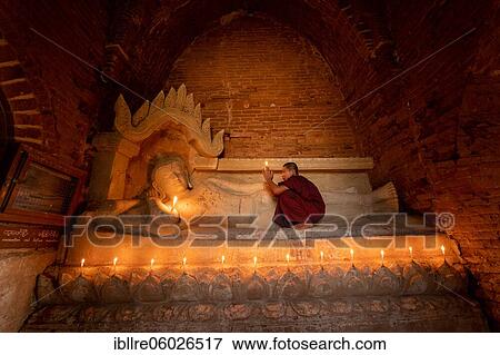 Buddhist young monk in red robe with red umbrella praying with candle in hand in a temple, Bagan, Myanmar, Asia View Large Photo Image Stock Photo - Buddhist young monk in red robe with red umbrella praying with candle in hand in a temple, Bagan, Myanmar, Asia. Fotosearch