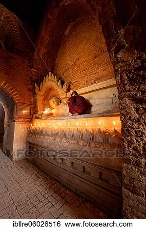 Buddhist young monk in red robe with red umbrella praying with candle in hand in a temple, Bagan, Myanmar, Asia View Large Photo Image Stock Photograph - Buddhist young monk in red robe with red umbrella praying with candle in hand in a temple, Bagan, Myanmar, Asia. Fotosearch