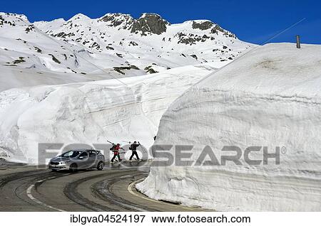 Car and two skiers in front of high snow walls, pass road to the Gotthard Pass, Canton Ticino, Switzerland, Europe View Large Photo Image Stock Photo - Car and two skiers in front of high snow walls, pass road to the Gotthard Pass, Canton Ticino, Switzerland, Europe. Fotosearch