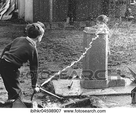Stock Photo - Children squirt with hose, England, Great Britain. Fotosearch