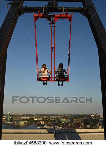 Stock Image - Children sway in the Swing 'Over The Edge high above the rooftops of Amsterdam on the A'DAM LOOKOUT, A'DAM TOWER, Amsterdam, North Holland, Holland, Netherlands. Fotosearch