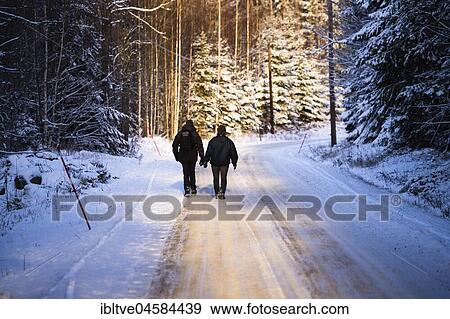 Couple, pedestrians walking on a road through snowy forest, Värmland, Sweden, Europe View Large Photo Image Stock Photo - Couple, pedestrians walking on a road through snowy forest, Värmland, Sweden, Europe. Fotosearch