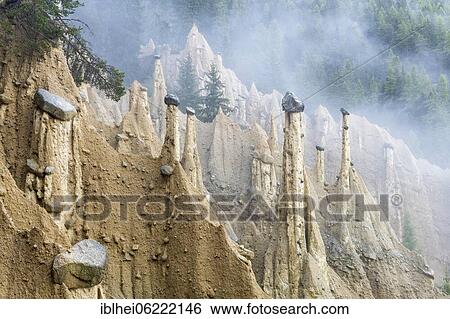 Stock Photograph - Earth pyramids near Perchau in the mist, South Tyrol, Italy, Europe. Fotosearch